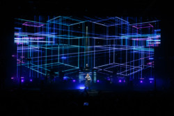 Pet Shop Boys perform in front of a bright LED screen for a crowd with their hands raised. Neil Tennant (front centre) stands in front of Chris Lowe (rear centre) and the supporting musicians at Budweiser Stage in Toronto, CANADA