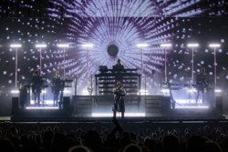 Pet Shop Boys perform in front of a bright LED screen for a large crowd. Neil Tennant (front centre) stands in front of Chris Lowe (rear centre) and the supporting musicians at Budweiser Stage in Toronto, CANADA
