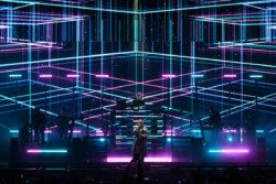 Pet Shop Boys perform in front of a bright LED screen for a crowd with their hands raised. Neil Tennant (front centre) stands in front of Chris Lowe (rear centre) and the supporting musicians at Budweiser Stage in Toronto, CANADA
