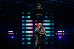 Neil Tennant of Pet Shop Boys performs in a silver metallic raincoat and sunglasses. Chris Lowe is seen in the background at Budweiser Stage in Toronto, CANADA