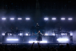Pet Shop Boys perform in front of a bright LED screen for a crowd with their hands raised. Neil Tennant (front centre) stands in front of Chris Lowe (rear centre) and the supporting musicians at Budweiser Stage in Toronto, CANADA