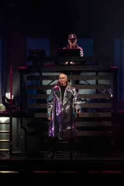 Neil Tennant of Pet Shop Boys performs in a silver metallic raincoat. Chris Lowe is seen in the background at Budweiser Stage in Toronto, CANADA